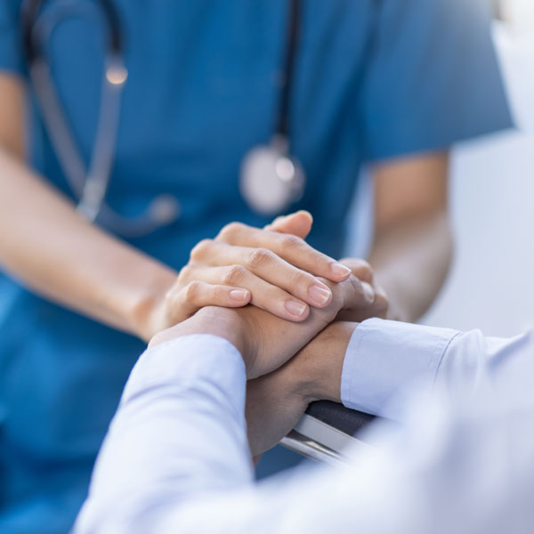 closeup of nurses hands comforting patient